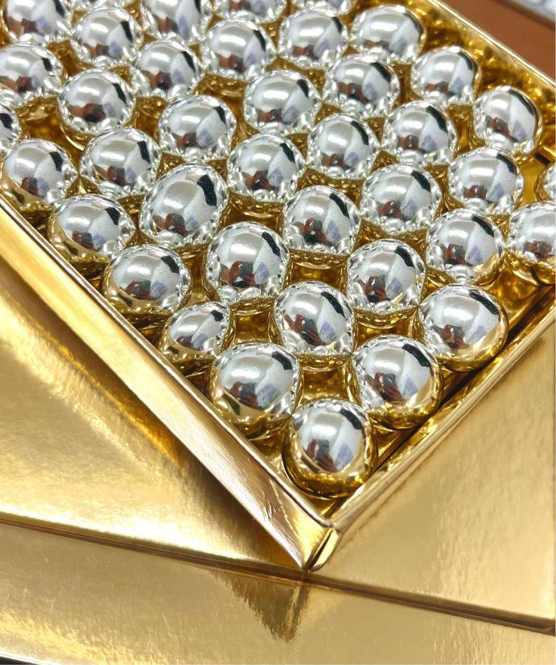 collezioni - scatola dorata con all'interno confetti  con nocciole al cioccolato color argento.