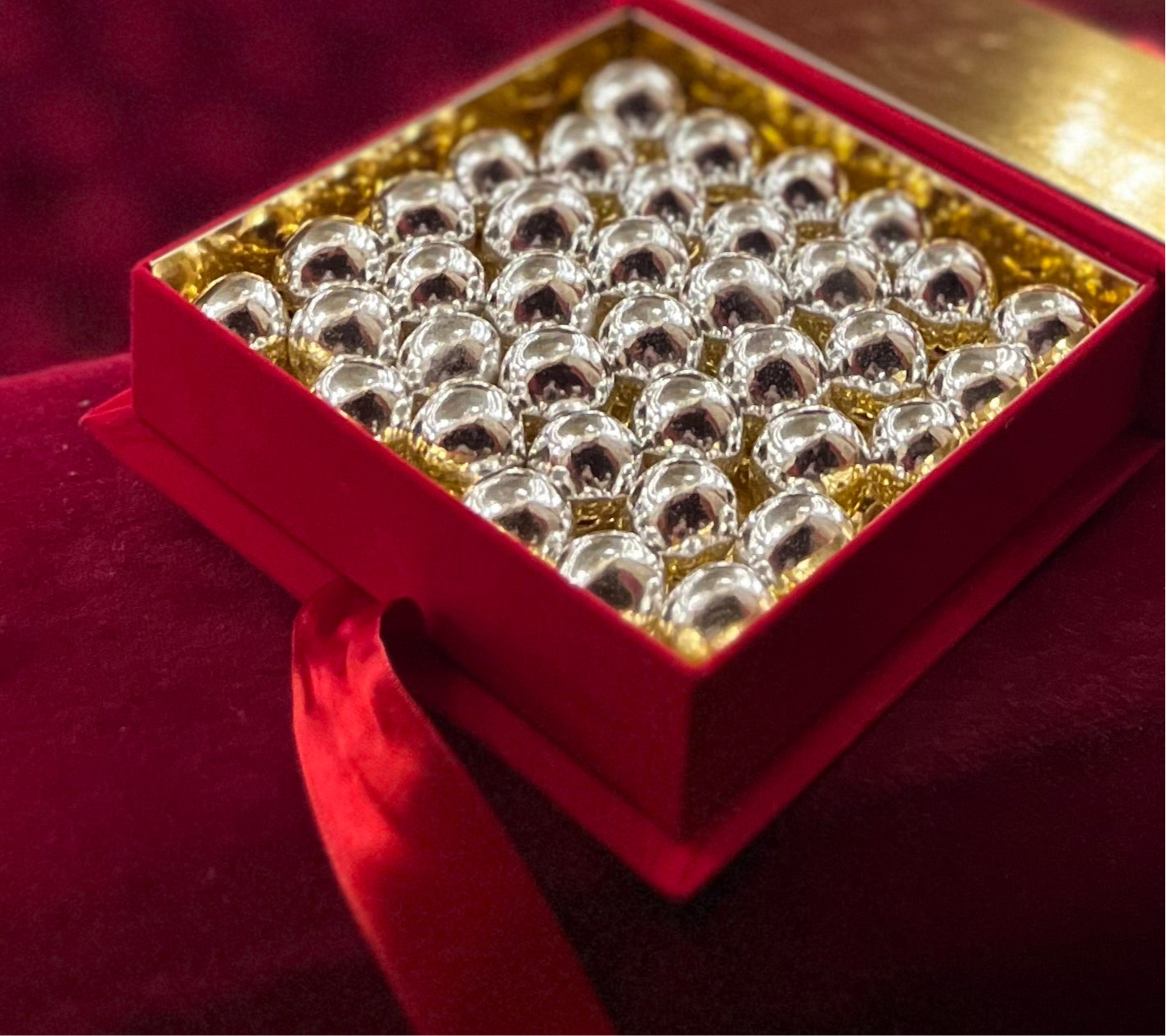 collezioni - Scatola di velluto rossa con all'interno Confetti con nocciole al cioccolato color argento.